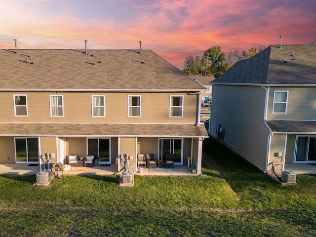 back house at dusk featuring a patio, central AC, a yard, and an outdoor hangout area