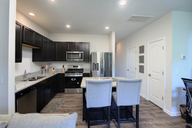 kitchen with a kitchen island, dark wood-type flooring, sink, a breakfast bar, and appliances with stainless steel finishes