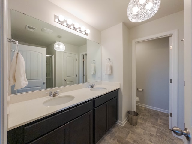 bathroom with toilet, vanity, and a shower with door