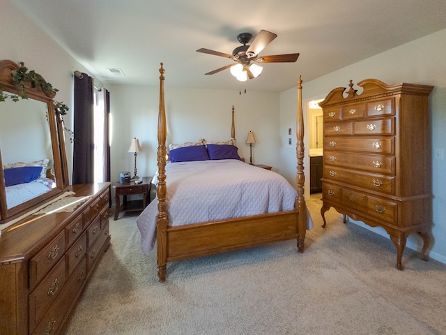 carpeted bedroom with ensuite bath and ceiling fan