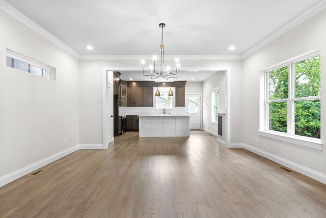 kitchen featuring decorative light fixtures, dark brown cabinets, an inviting chandelier, light hardwood / wood-style floors, and a center island