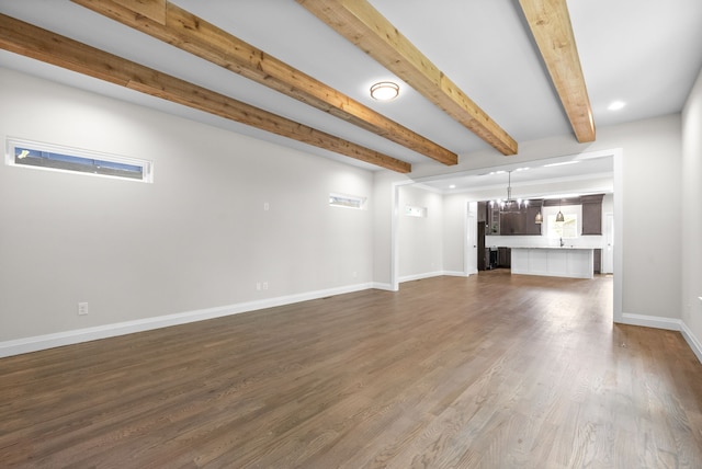 unfurnished living room featuring dark wood-type flooring, beamed ceiling, and a notable chandelier