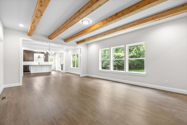 unfurnished living room with dark hardwood / wood-style flooring, beamed ceiling, and an inviting chandelier