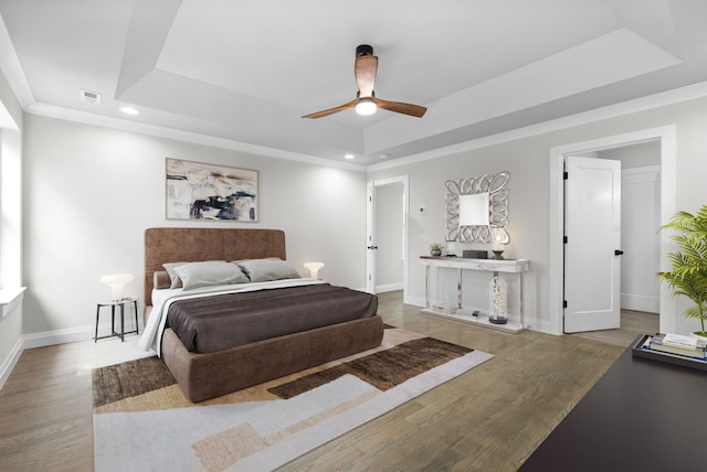 bedroom with hardwood / wood-style flooring, ceiling fan, and a tray ceiling