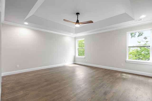 spare room featuring dark hardwood / wood-style flooring, ceiling fan, and a tray ceiling