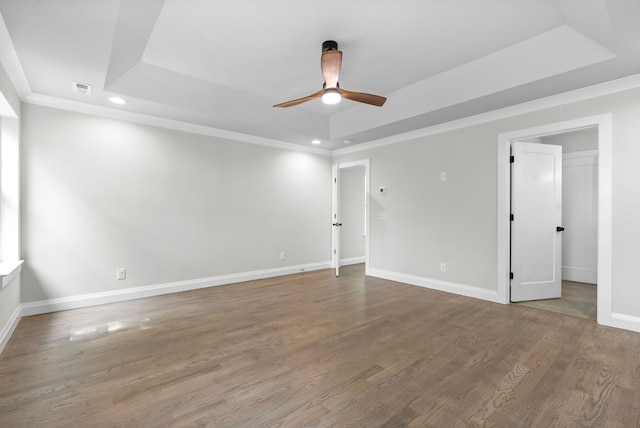 empty room featuring hardwood / wood-style flooring, a raised ceiling, and ceiling fan