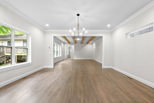 unfurnished living room with hardwood / wood-style floors, a notable chandelier, ornamental molding, and plenty of natural light