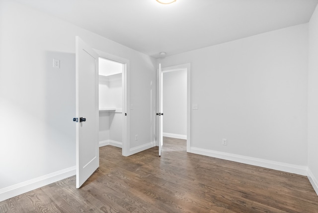 unfurnished bedroom featuring a spacious closet, wood-type flooring, and a closet