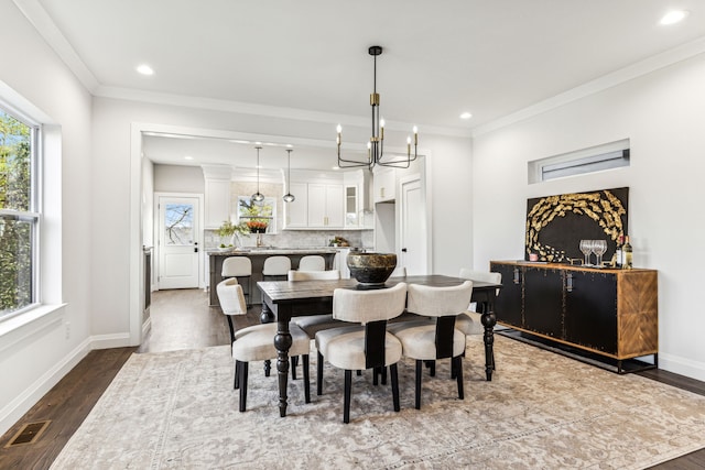 dining space featuring dark hardwood / wood-style floors, crown molding, and an inviting chandelier