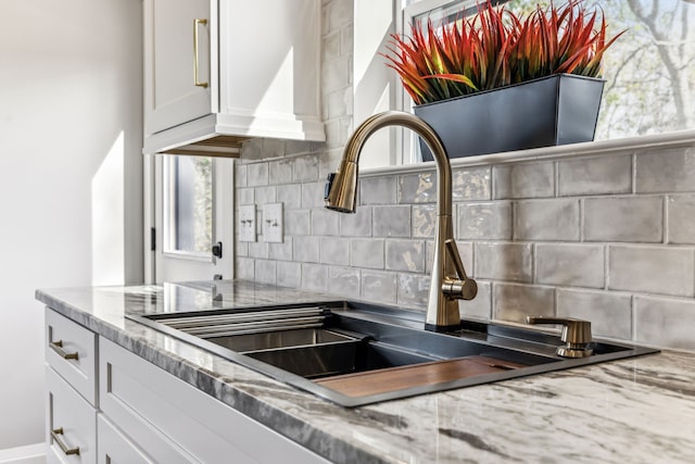 room details with white cabinets, light stone countertops, and tasteful backsplash