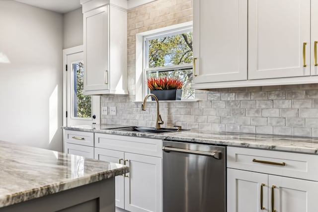 kitchen featuring light stone counters, white cabinetry, decorative backsplash, sink, and dishwasher