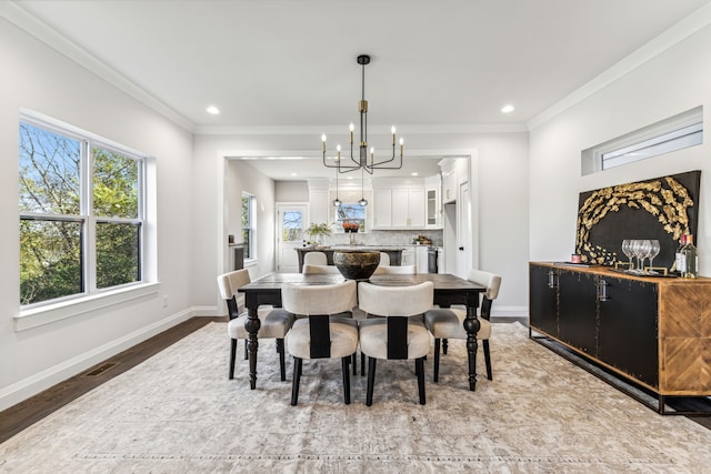 dining space with a chandelier, light wood-type flooring, and crown molding