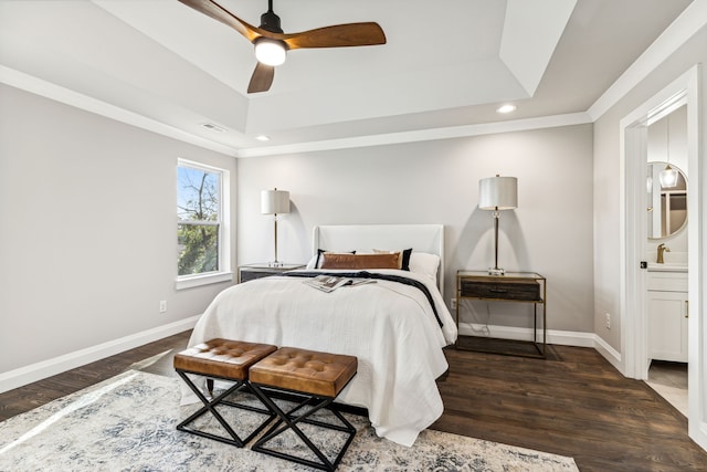 bedroom with connected bathroom, a raised ceiling, sink, dark wood-type flooring, and ceiling fan