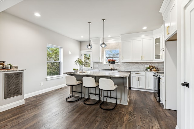 kitchen with dark hardwood / wood-style flooring, white cabinets, sink, a kitchen island, and electric range