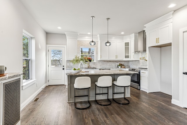 kitchen featuring pendant lighting, electric stove, dark hardwood / wood-style floors, wall chimney range hood, and white cabinetry