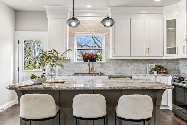 kitchen with stainless steel appliances, white cabinetry, light stone counters, and a center island