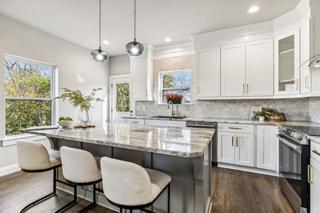 kitchen featuring white cabinetry, appliances with stainless steel finishes, decorative light fixtures, sink, and a center island