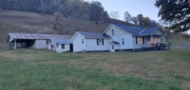 rear view of house with covered porch and a lawn