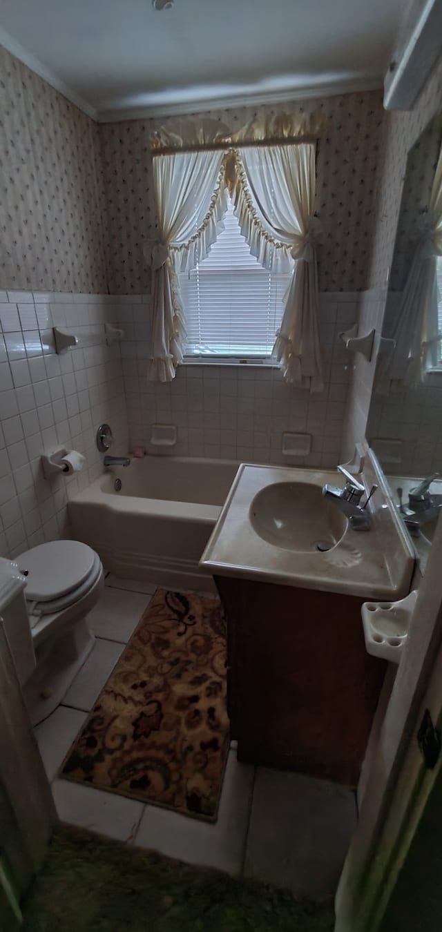 bathroom with toilet, a tub, vanity, and tile walls