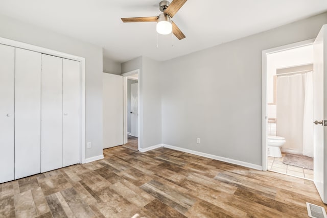 unfurnished bedroom with a closet, wood-type flooring, ceiling fan, and ensuite bathroom