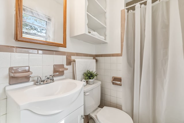 bathroom with tile walls, curtained shower, vanity, and toilet