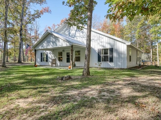 back of property with covered porch and a yard