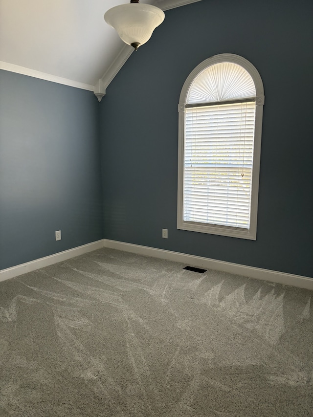 empty room featuring crown molding, vaulted ceiling, and carpet