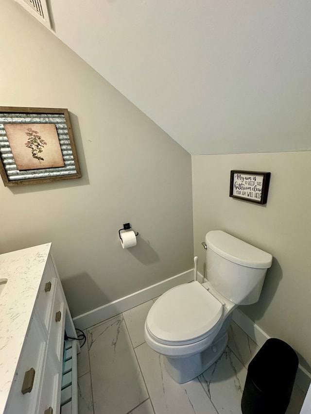 bathroom featuring vanity, toilet, and vaulted ceiling