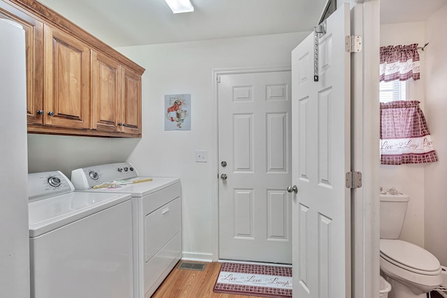 washroom featuring cabinets, washer and clothes dryer, and light wood-type flooring