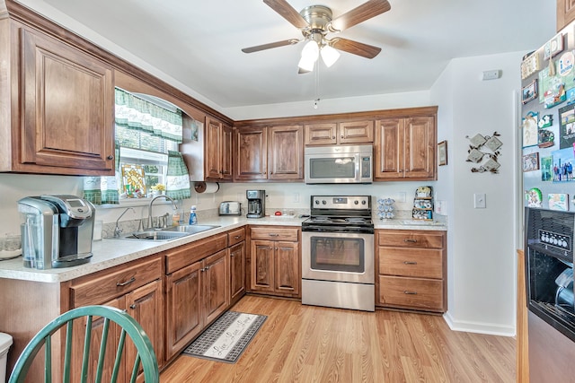 kitchen with appliances with stainless steel finishes, light hardwood / wood-style flooring, sink, and ceiling fan