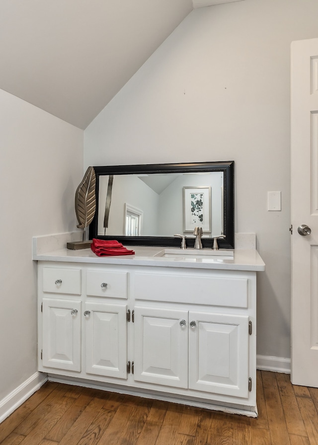 interior space with vanity, hardwood / wood-style flooring, and vaulted ceiling