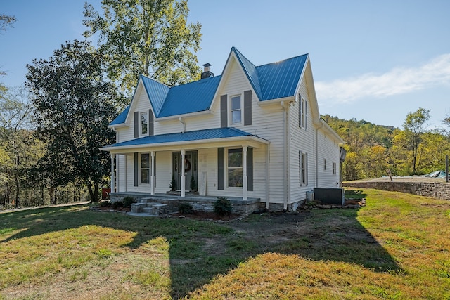 farmhouse with central air condition unit, a front yard, and covered porch