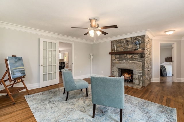 sitting room with crown molding, wood-type flooring, a fireplace, and ceiling fan