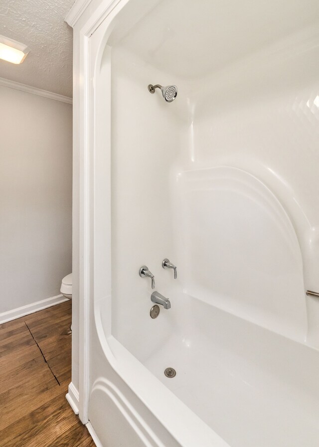 bathroom with shower / bathing tub combination, a textured ceiling, wood-type flooring, and toilet