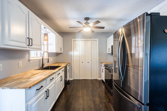 kitchen with dark wood-type flooring, stainless steel appliances, wood counters, sink, and white cabinets