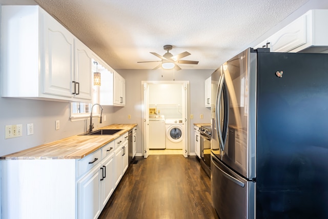 kitchen with appliances with stainless steel finishes, sink, washing machine and dryer, butcher block counters, and white cabinetry