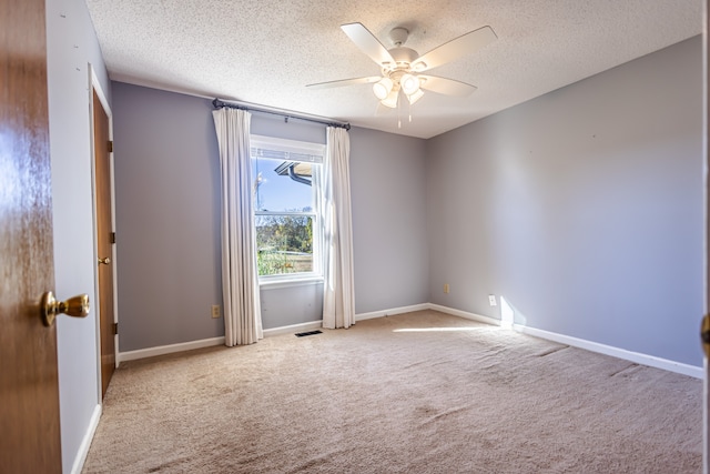 spare room featuring ceiling fan, light carpet, and a textured ceiling