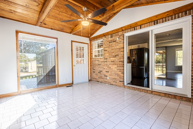 tiled empty room featuring brick wall, lofted ceiling with beams, wooden ceiling, and ceiling fan