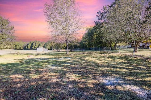 yard at dusk featuring a storage shed