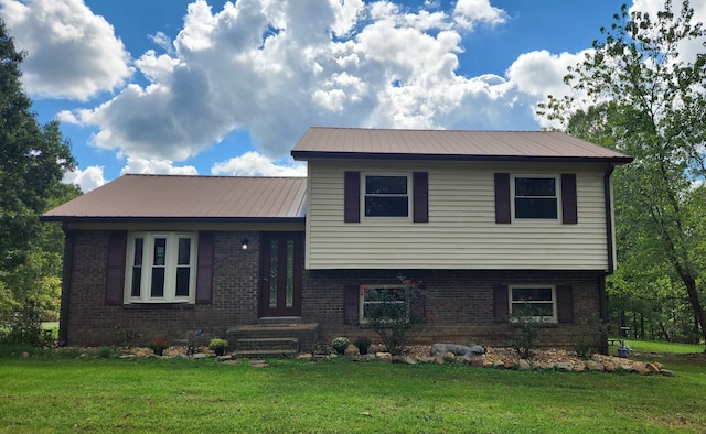 split level home with brick siding, metal roof, and a front yard