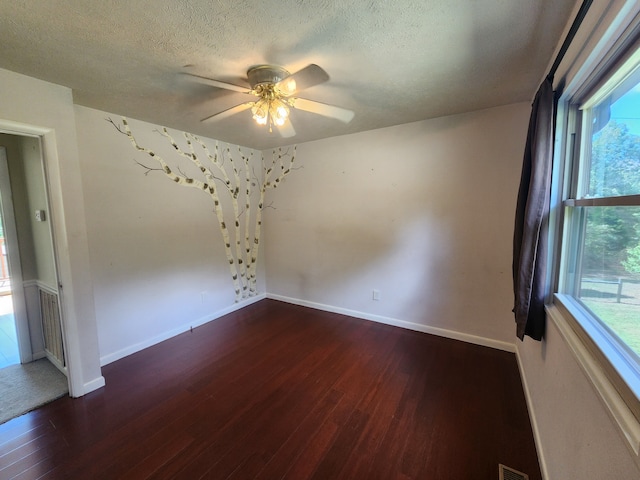 spare room featuring a textured ceiling, ceiling fan, and dark wood-type flooring