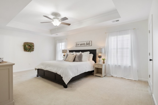 carpeted bedroom with ornamental molding, ceiling fan, multiple windows, and a raised ceiling