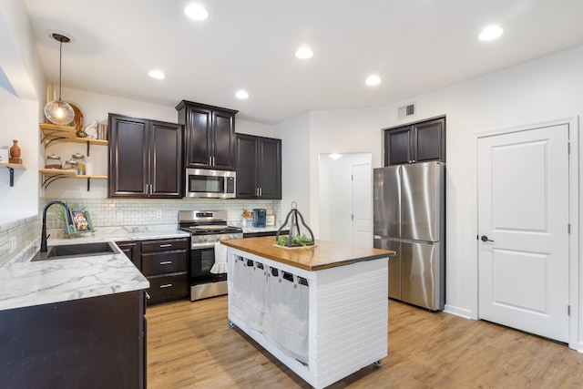 kitchen with decorative backsplash, sink, pendant lighting, appliances with stainless steel finishes, and light hardwood / wood-style floors