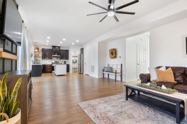 living room with sink, light wood-type flooring, and ceiling fan