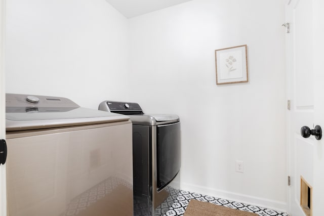 clothes washing area featuring light tile patterned flooring and separate washer and dryer