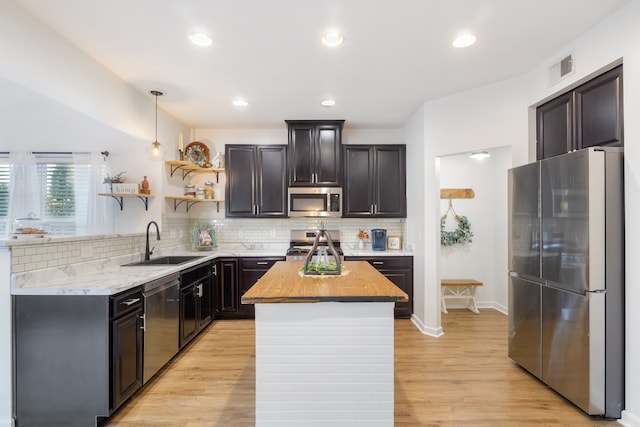 kitchen with appliances with stainless steel finishes, light hardwood / wood-style flooring, wood counters, and sink