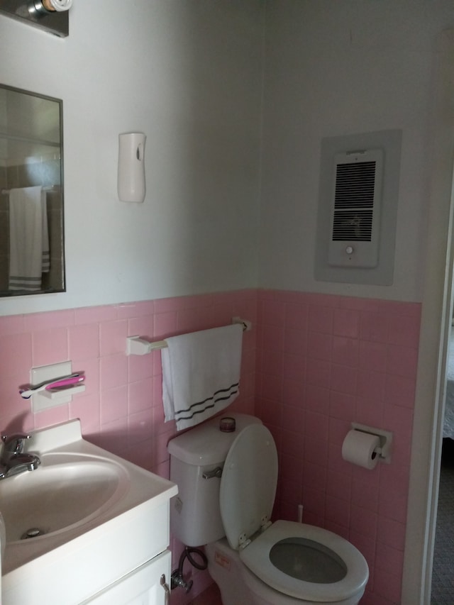 bathroom featuring vanity, toilet, tile walls, and heating unit