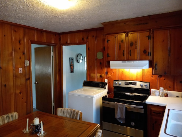 kitchen with washer / dryer, stainless steel electric range, a textured ceiling, wooden walls, and sink