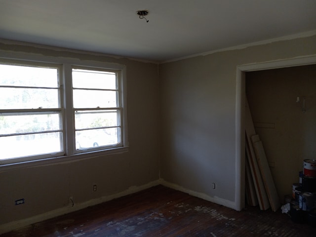 empty room with dark wood-type flooring and crown molding