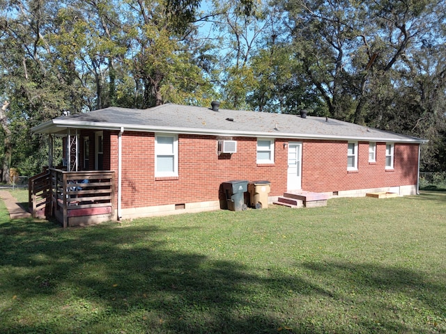 rear view of house with a lawn and a wall mounted air conditioner